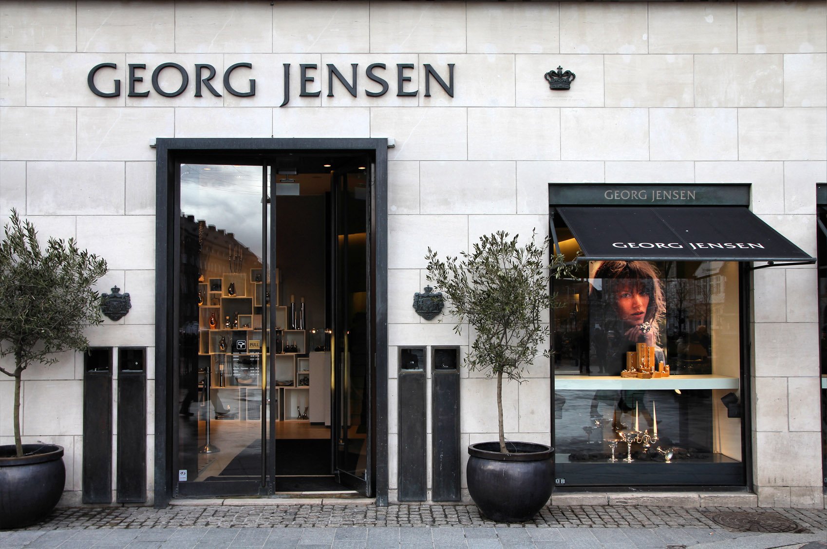Exteriör av en Georg Jensen-butik med stort skyltfönster och varumärkesskyltar ovanför entrén.