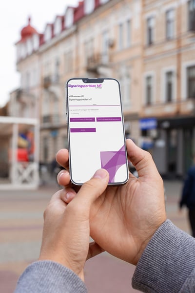 En person håller i en smartphone som visar inloggningssidan för 