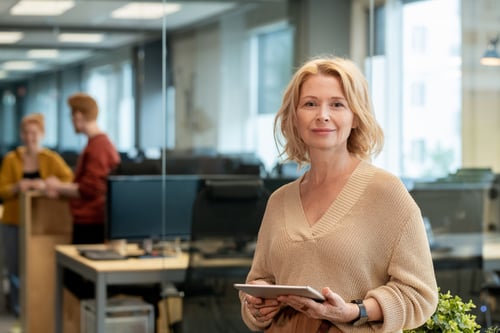 mature-blond-businesswoman-casualwear-standing-large-modern-office-using-tablet-against-two-young-colleagues mature-blond-businesswoman-casualwear-standing-large-modern-office-using-tablet-against-two-young-colleagues